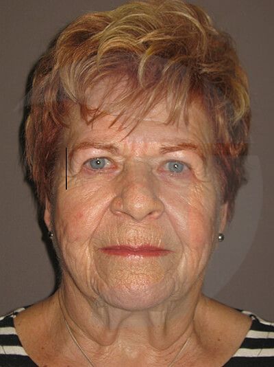 Close-up of a person with short, reddish-blonde hair and blue eyes, looking directly at the camera.