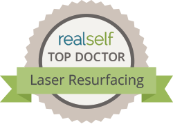 RealSelf Top Doctor badge for Laser Resurfacing; green ribbon with text, beige and gray round design.