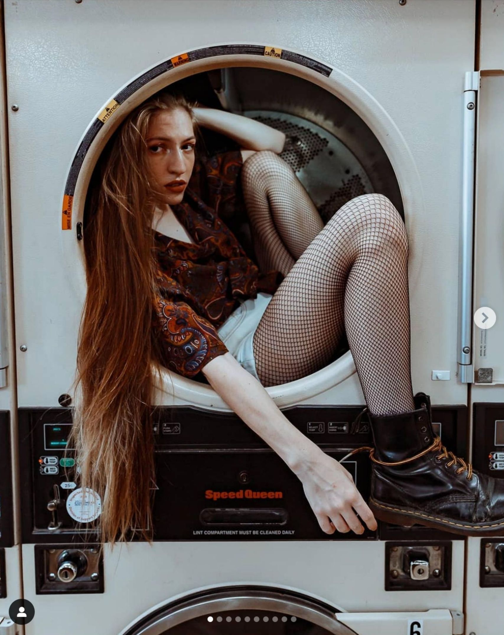 A woman with long hair is sitting in a washing machine.