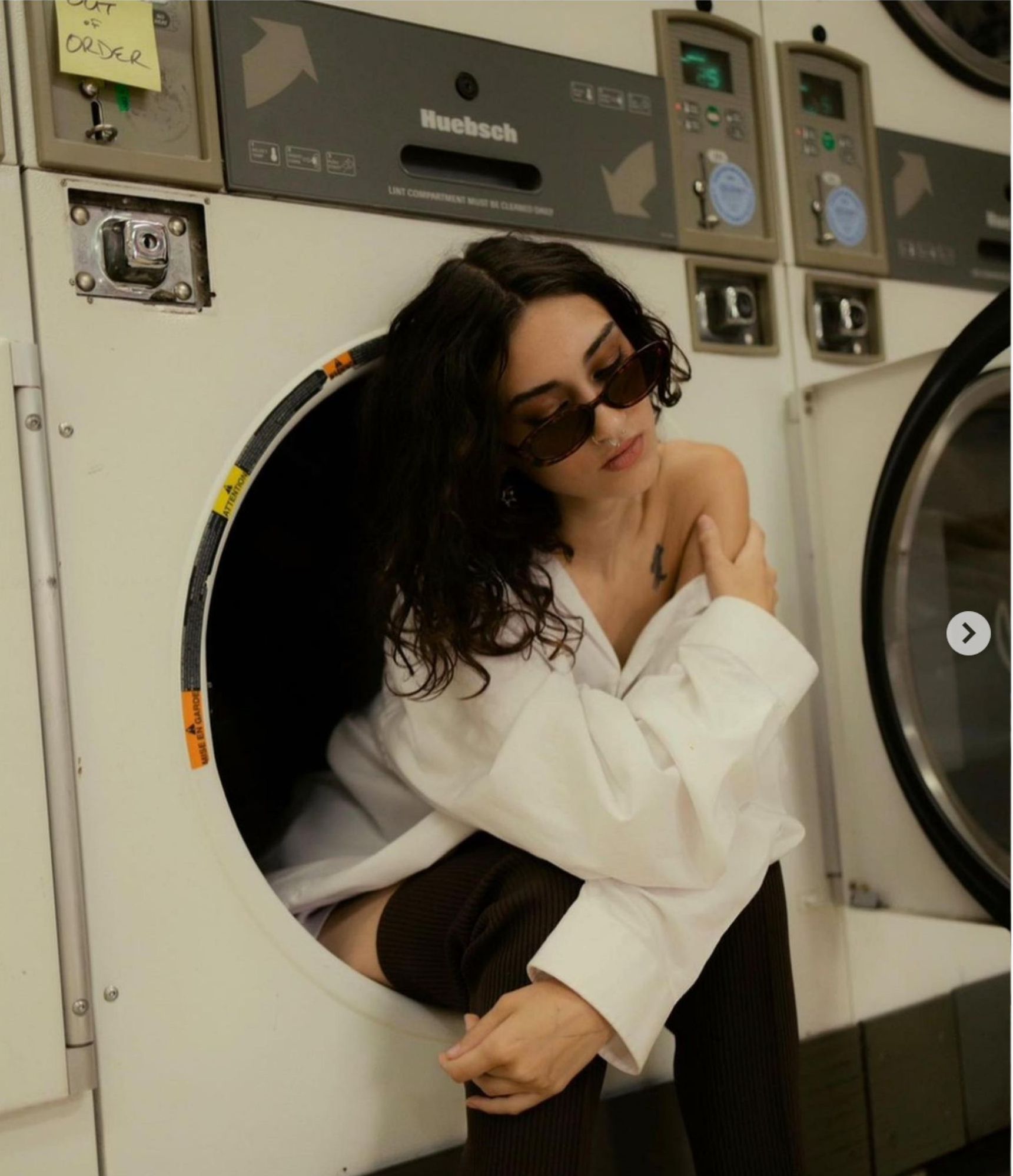 A woman wearing sunglasses is sitting in a washing machine