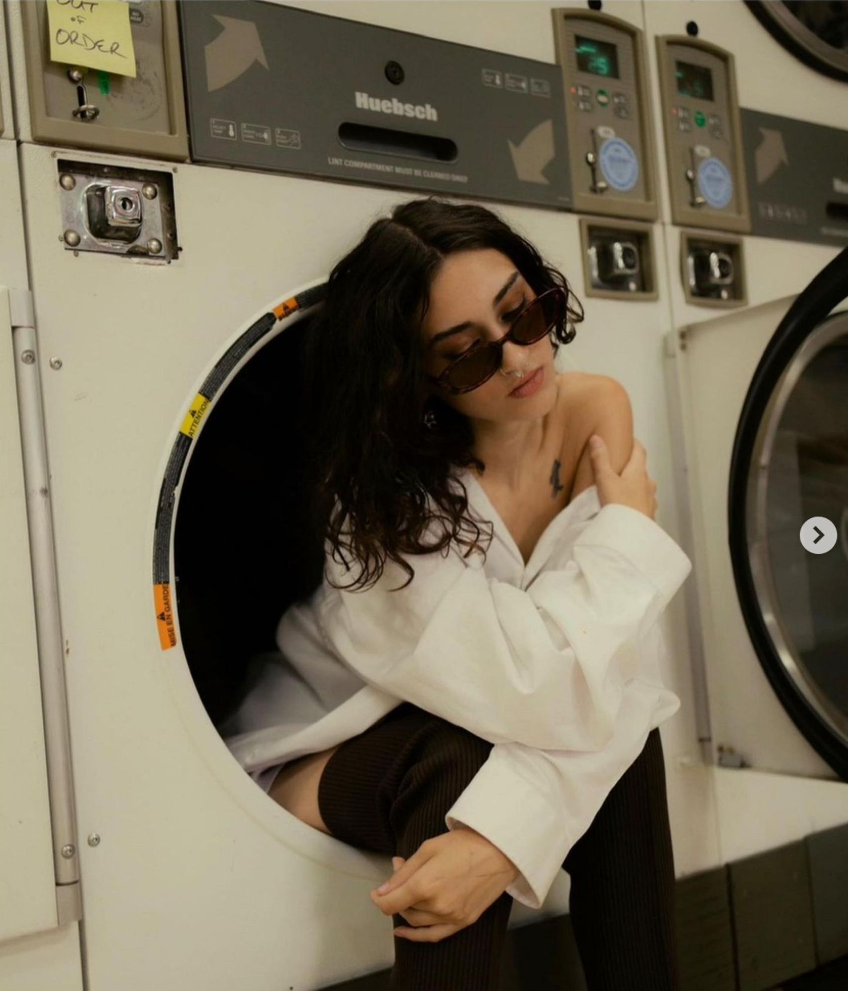 A woman wearing sunglasses is sitting in a washing machine