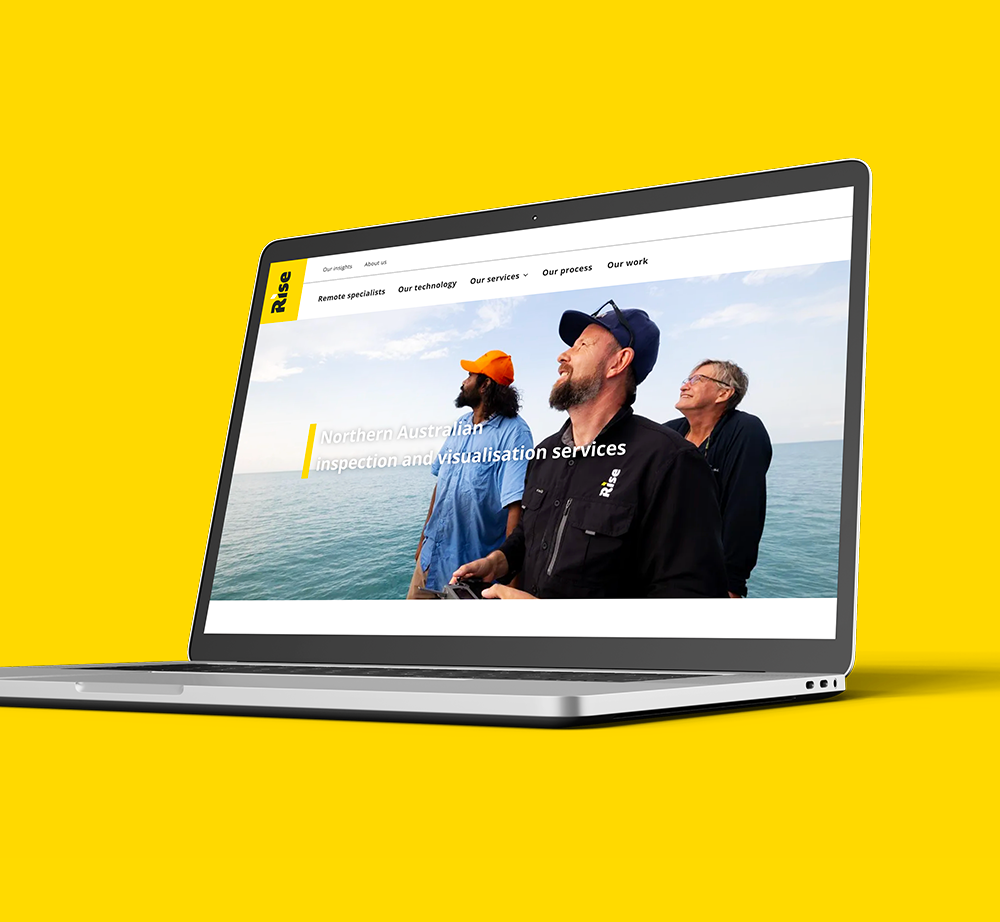 A laptop computer is sitting on a yellow surface with a website on the screen.