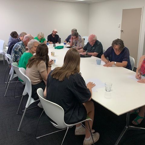 A group of people are sitting around a table in a room.