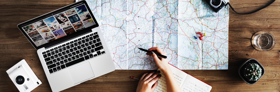 A person is sitting at a table with a laptop and a map.