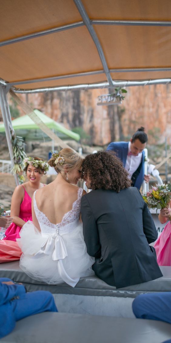 A bride and groom are sitting on a boat with their wedding party.