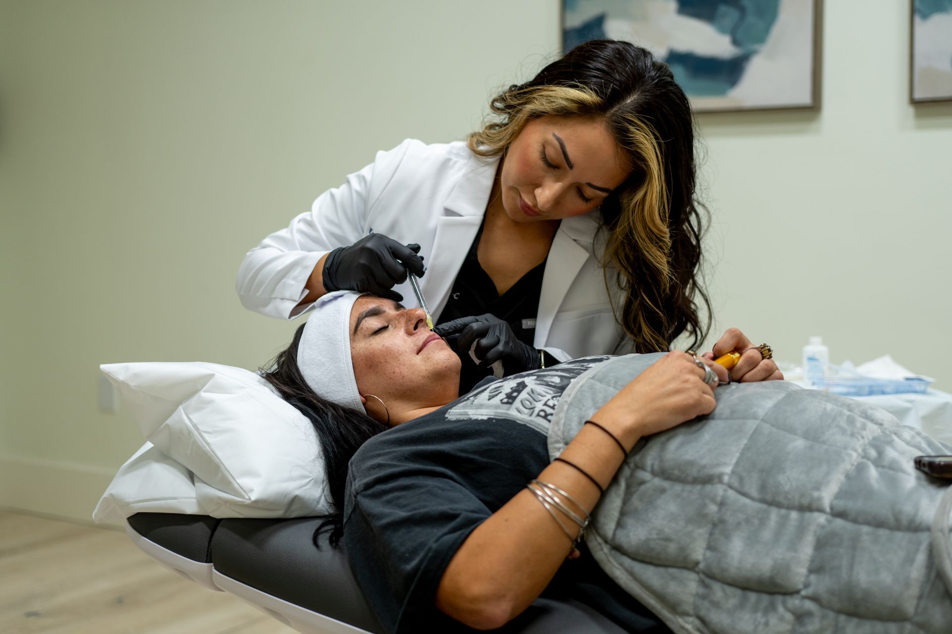 a woman is laying on a bed getting a facial treatment from a doctor .