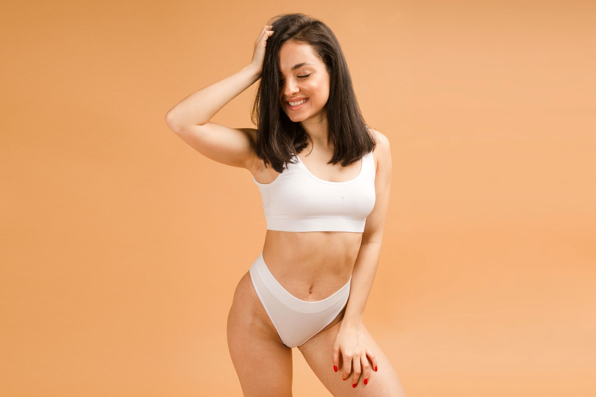 a woman in white underwear is standing on a beige background .