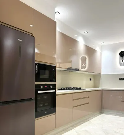 Cuisine moderne avec des armoires rose pâle brillantes, des appareils électroménagers intégrés et un réfrigérateur marron.