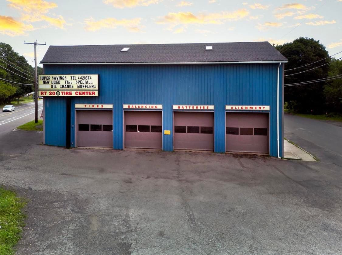 Blue auto repair shop with three garage doors and a sign.