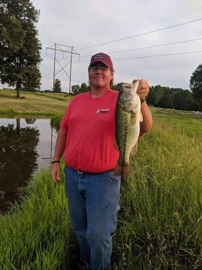 A man in a red shirt is holding a large fish in his hands.
