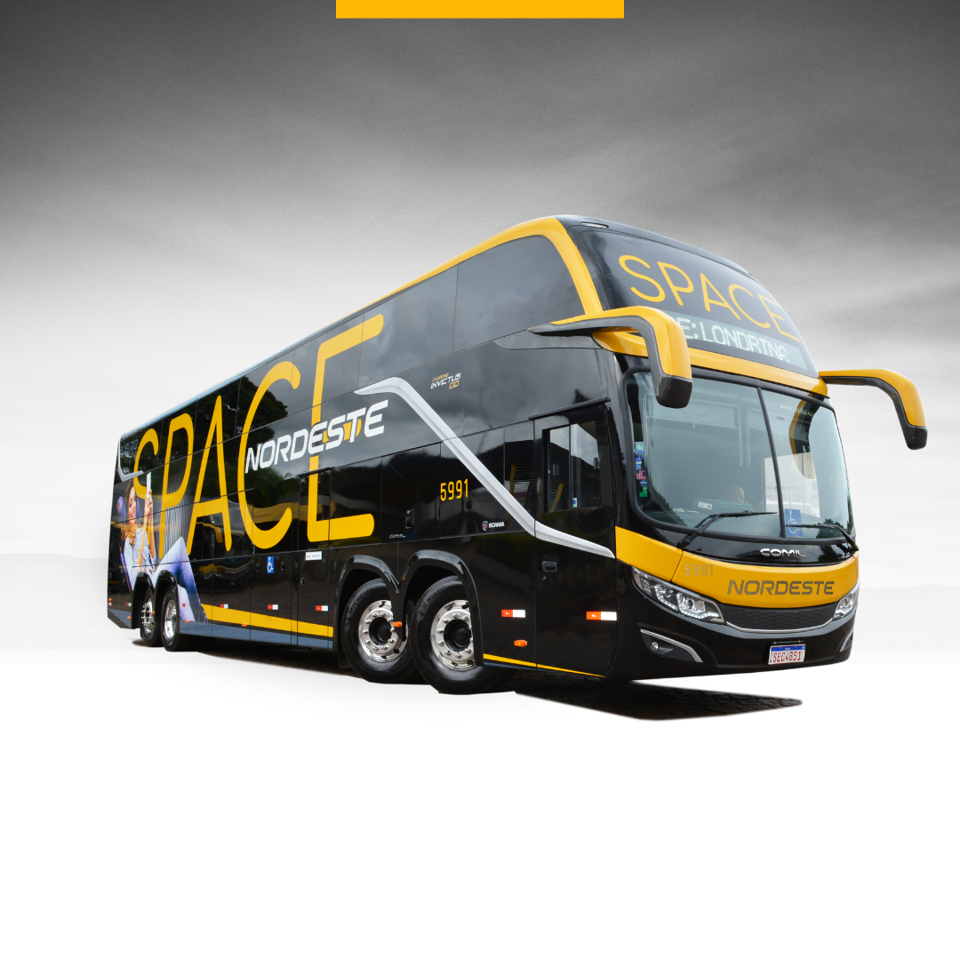 Ônibus estacionado em um posto de gasolina e na frente da imagem há um canteiro com flores e grama