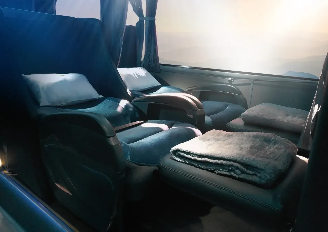 Imagem do interior do ônibus Leito Cama, com um cobertor no assento