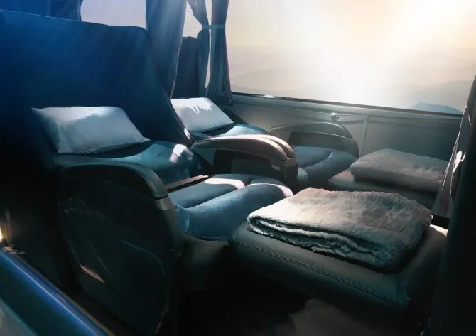 Imagem do interior do ônibus Leito Cama, com um cobertor no assento