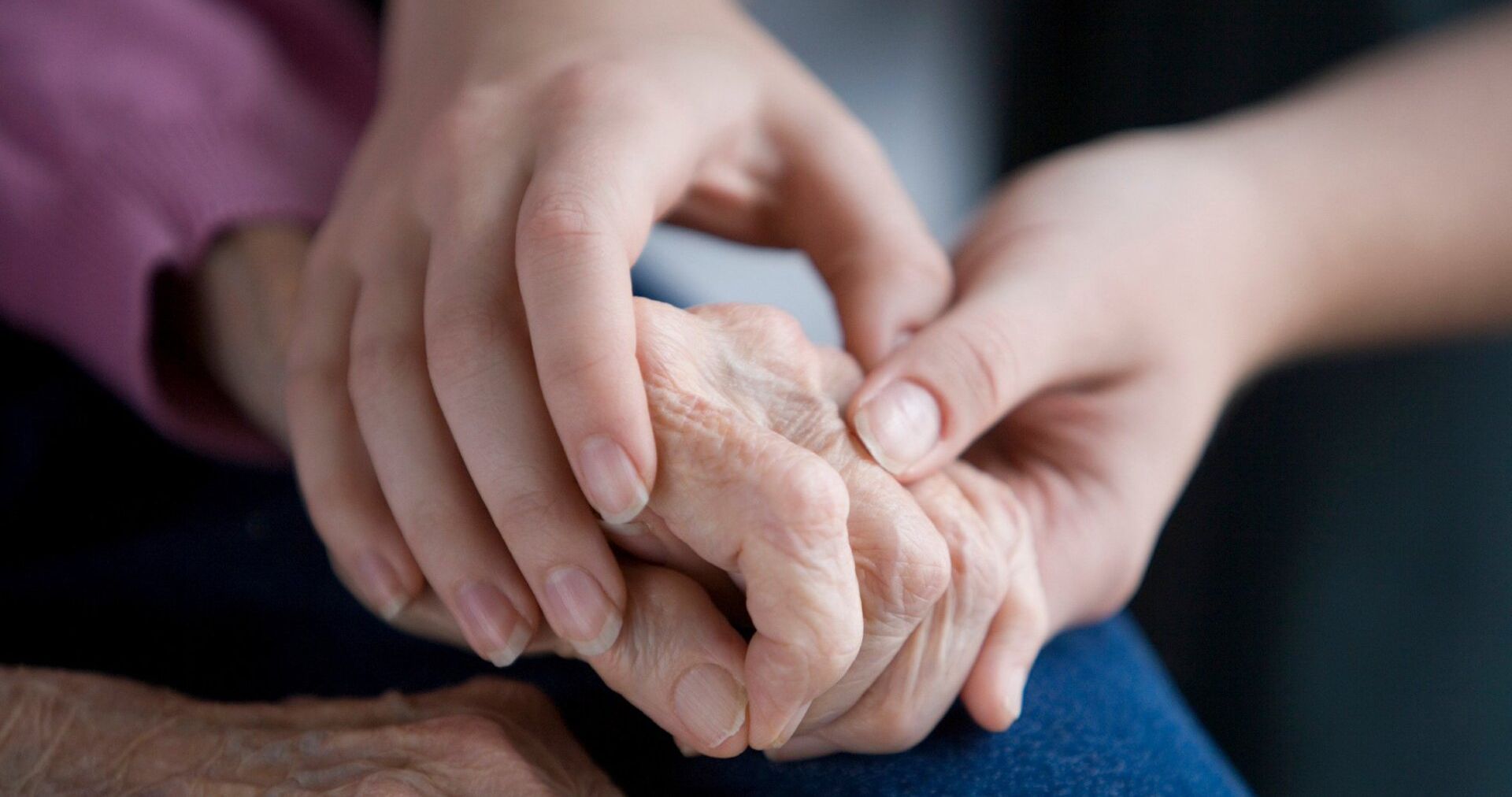 A woman is holding the hand of an older woman.