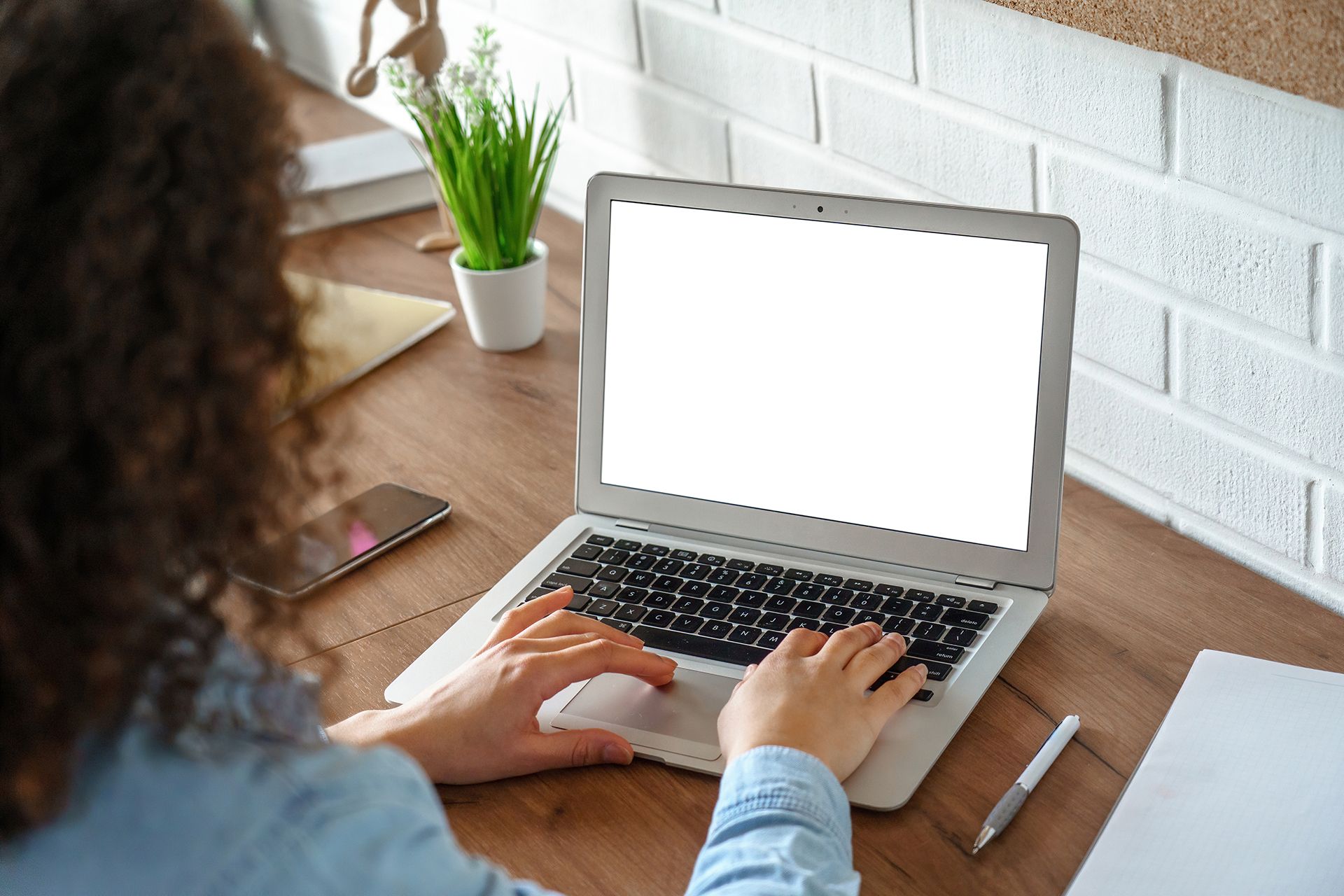 A woman is typing on a laptop computer with a white screen.