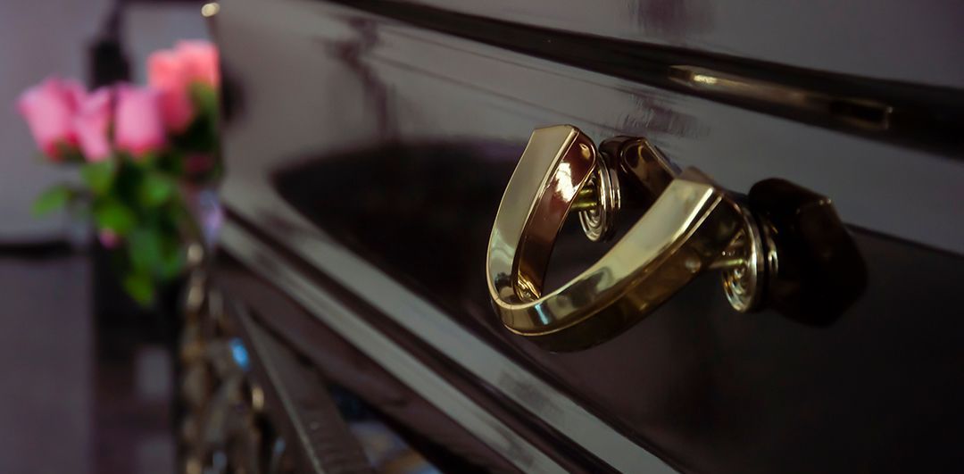 A close up of a gold handle on a black piano.