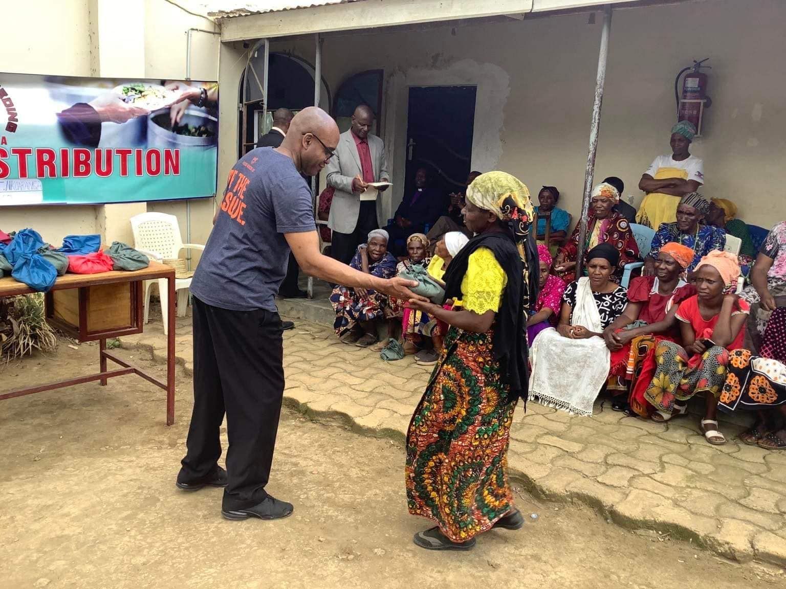 A man is giving a woman a gift in front of a group of people.