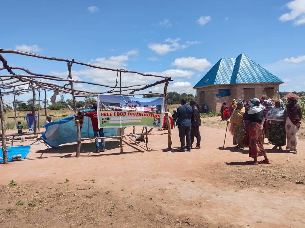 A group of people are standing in front of a sign that says tell us what