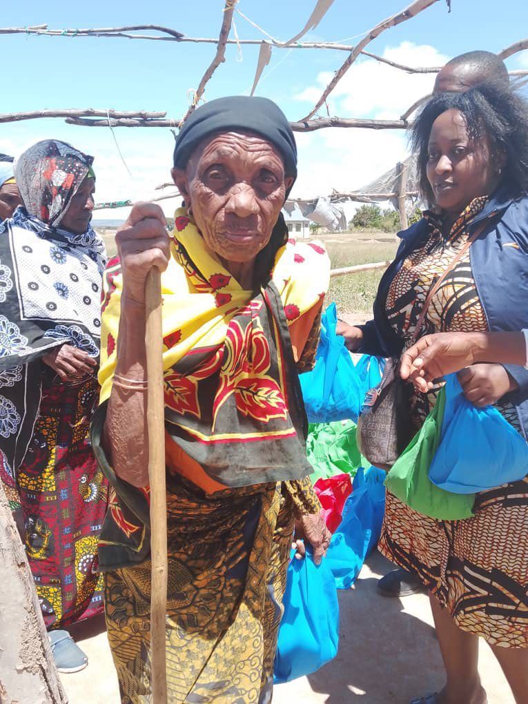 An elderly woman is holding a wooden stick in her hand