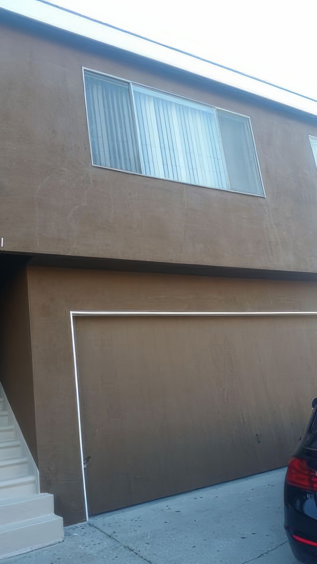 A car is parked in front of a brown building