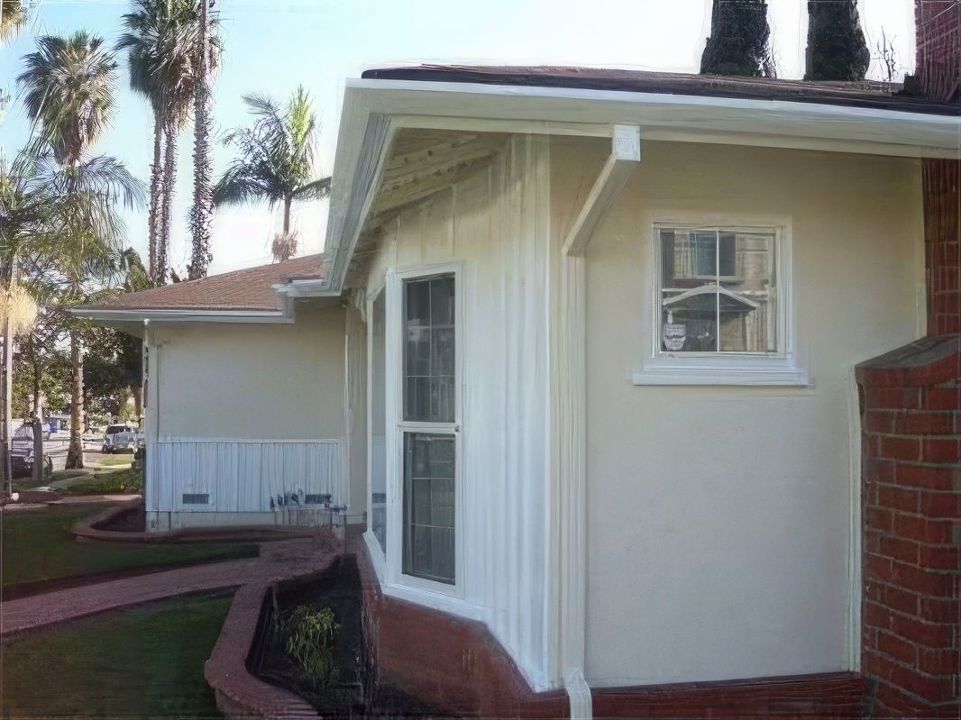 A white house with a bay window and a brick wall