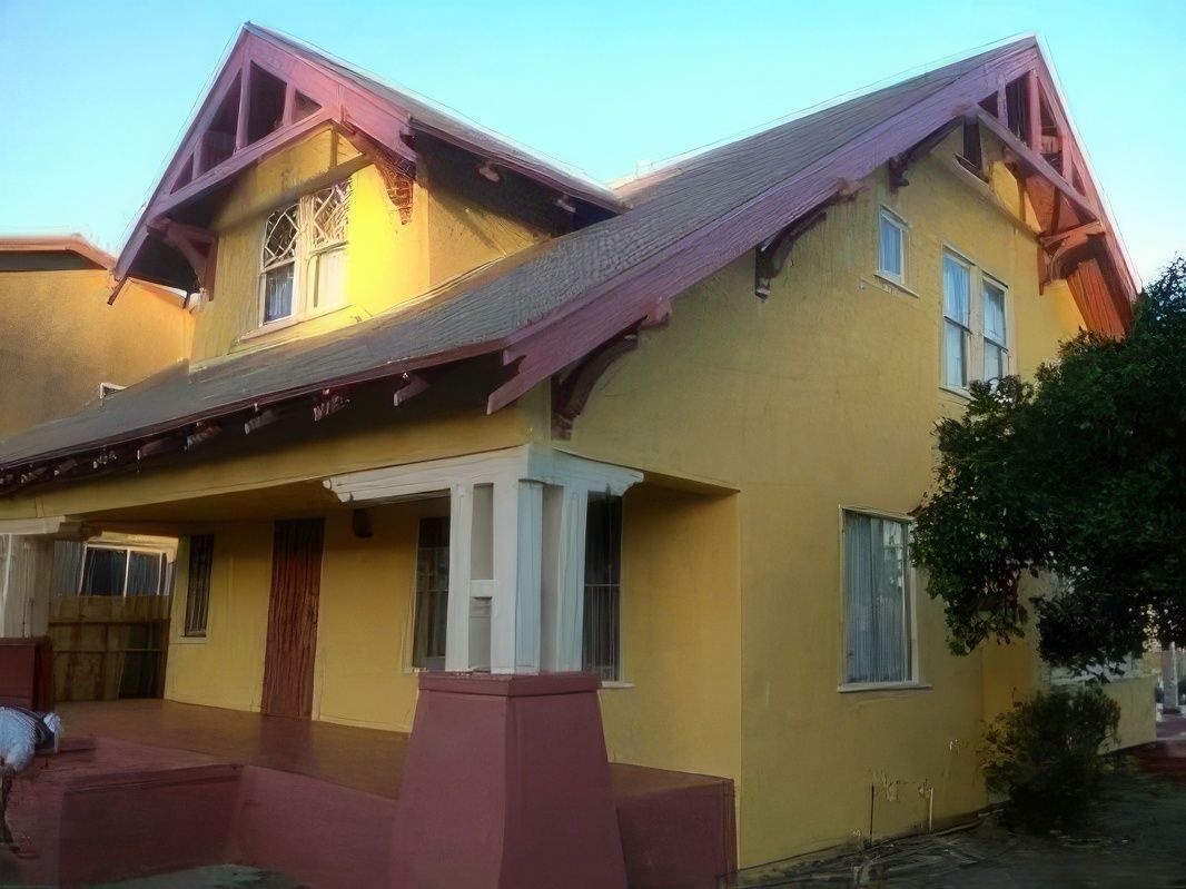 A yellow house with a red roof and a sign that says hi