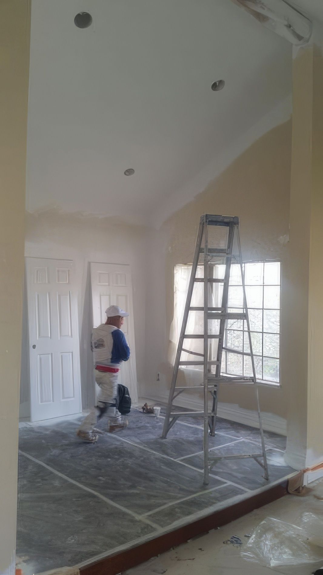 A man is painting a room with a ladder in the background.