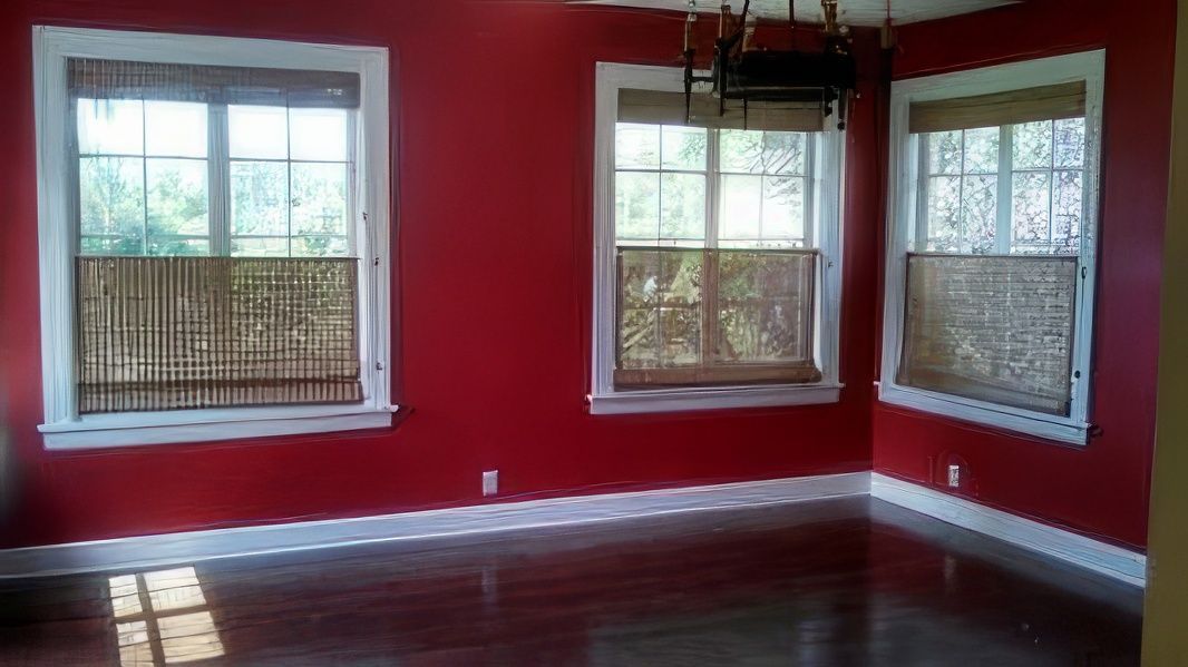 An empty room with red walls and two windows.