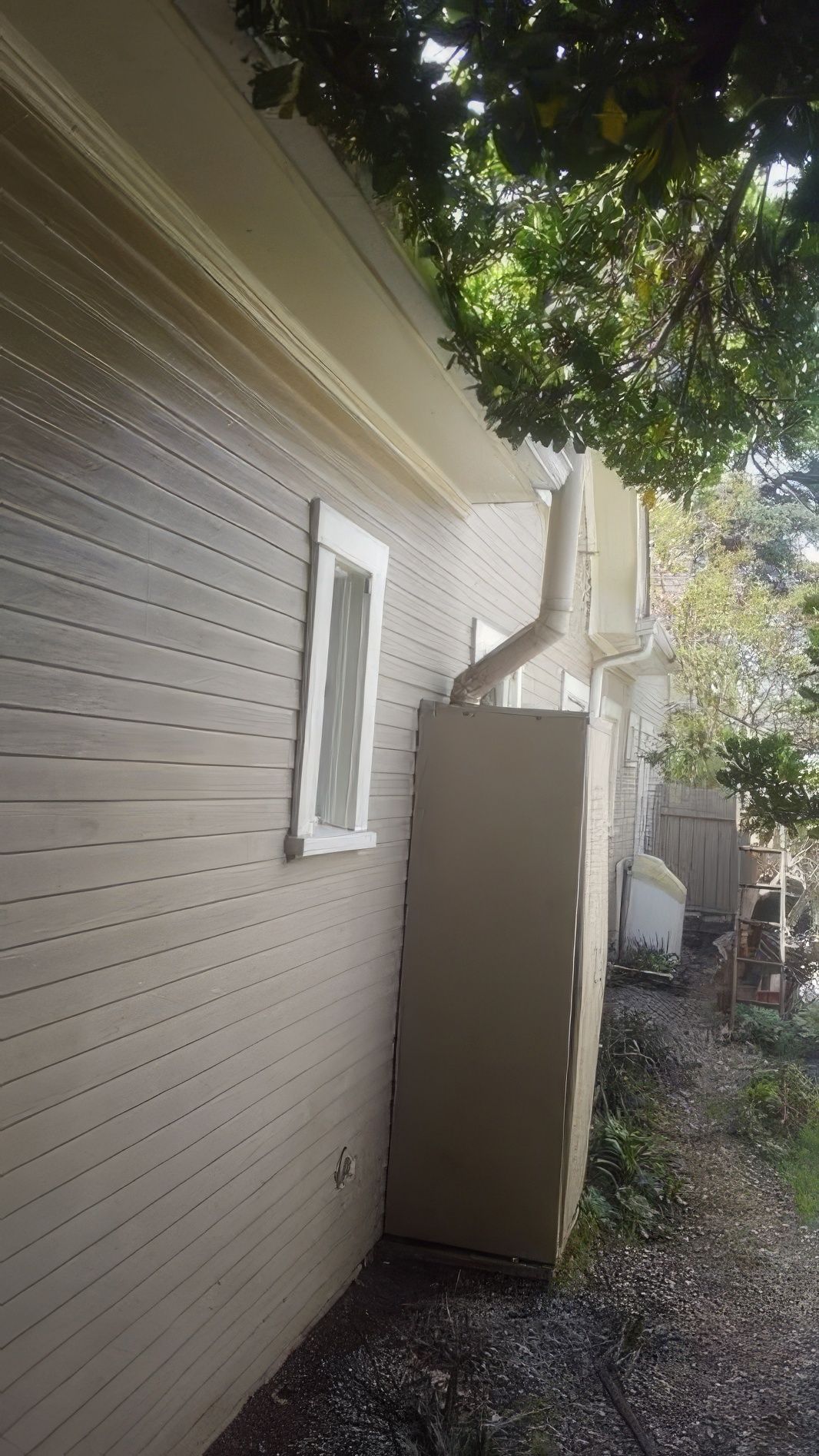 A white house with a window and a drain on the side of it.