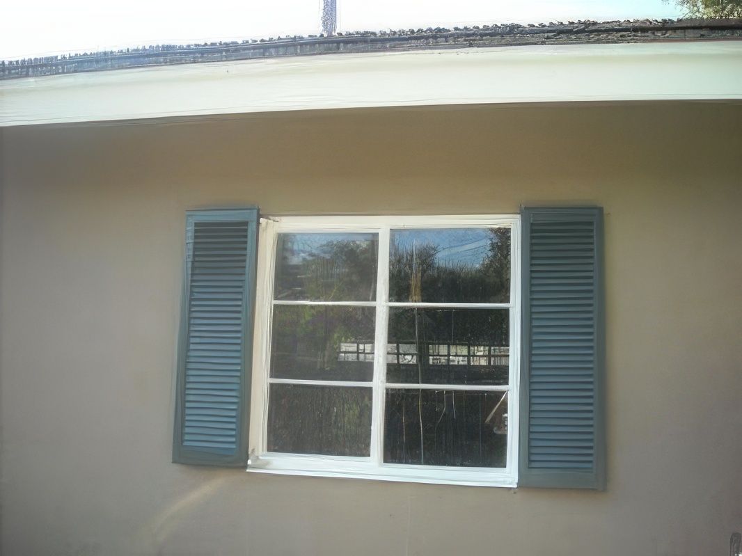 A window with blue shutters on the side of a house