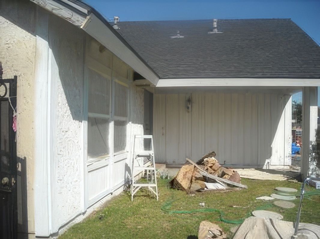A white house with a black roof and a ladder in front of it