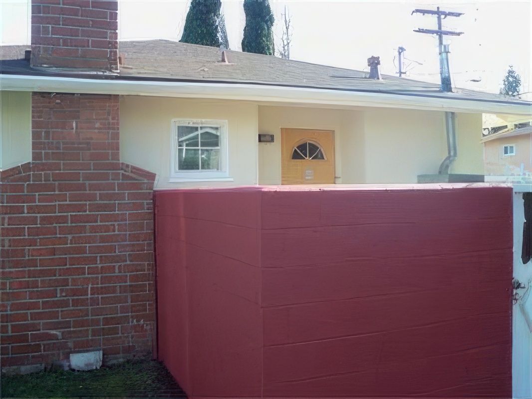 A white house with a red fence and a brick chimney