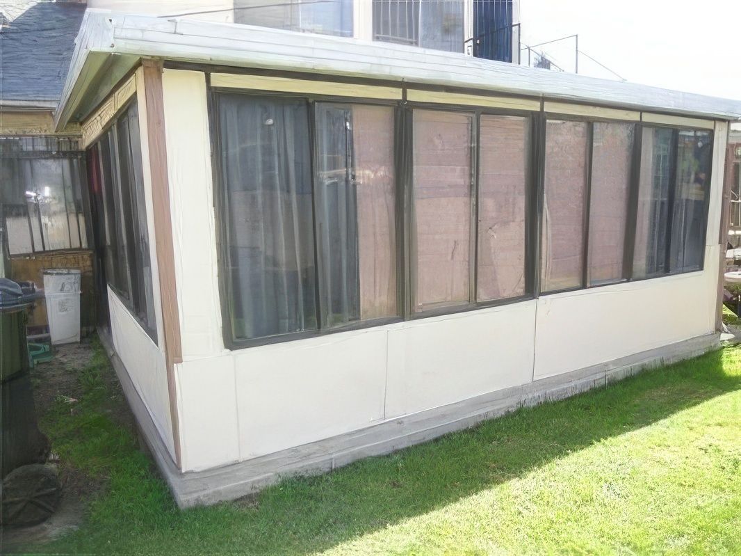 A white house with a lot of windows is sitting on top of a lush green lawn.