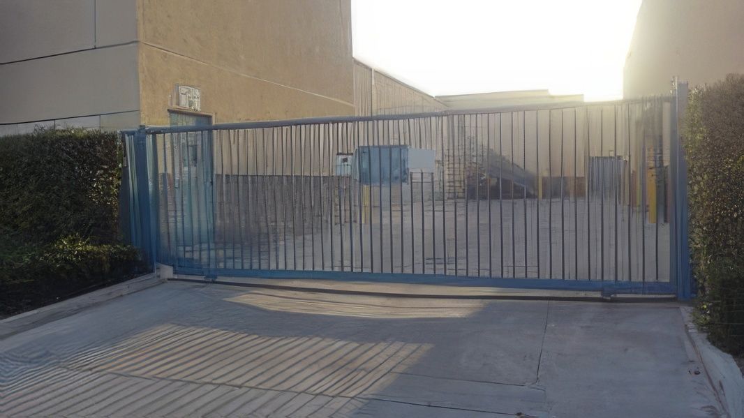 A blue sliding gate is closed in front of a building.