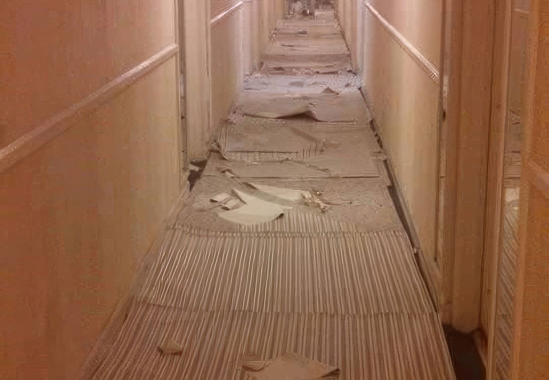 A long hallway with a broken carpet on the floor.