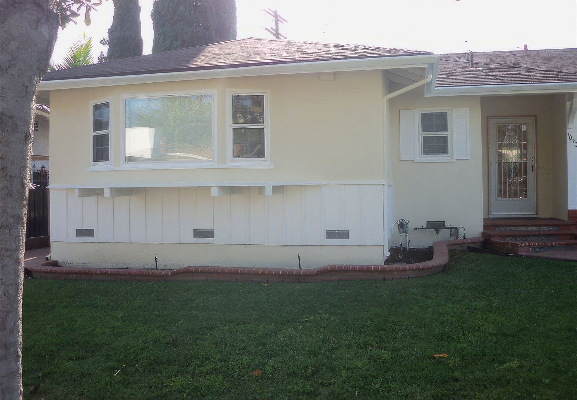 A white house with a lush green lawn in front of it