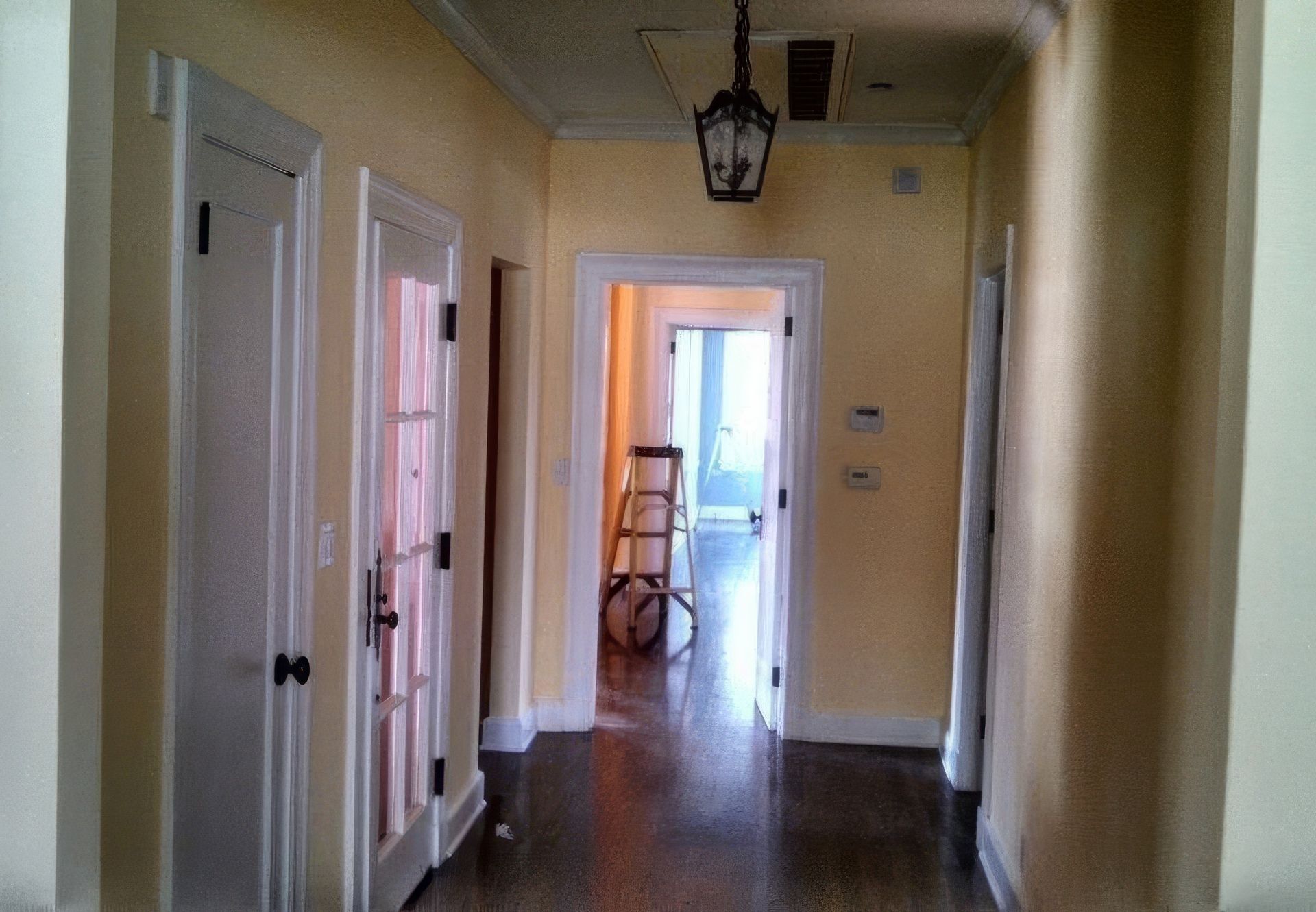 A hallway with yellow walls and white doors