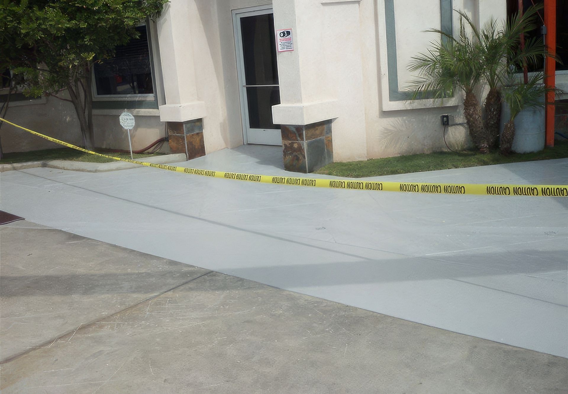 A concrete driveway is surrounded by yellow caution tape