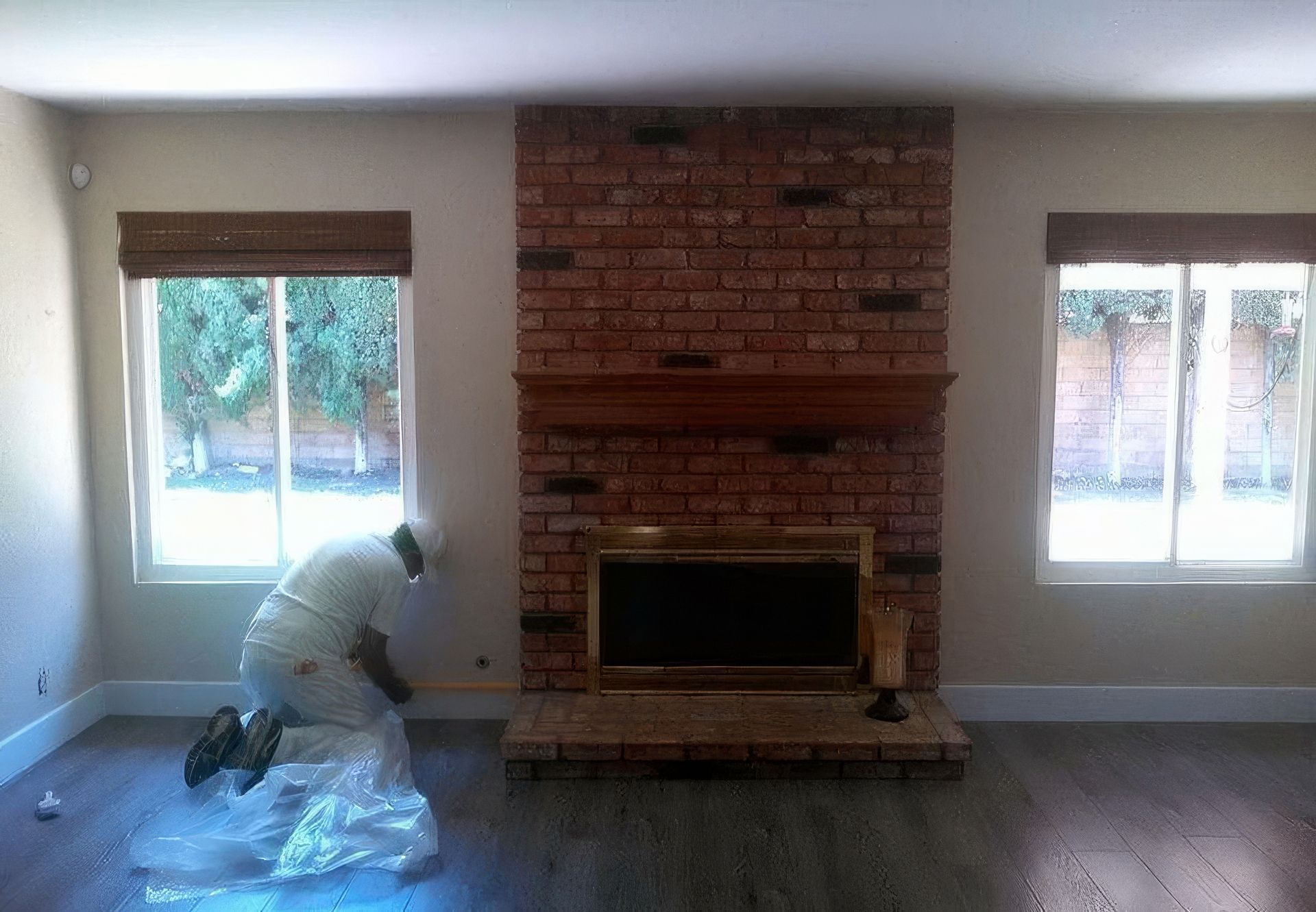 A man is kneeling in front of a fireplace in a living room.