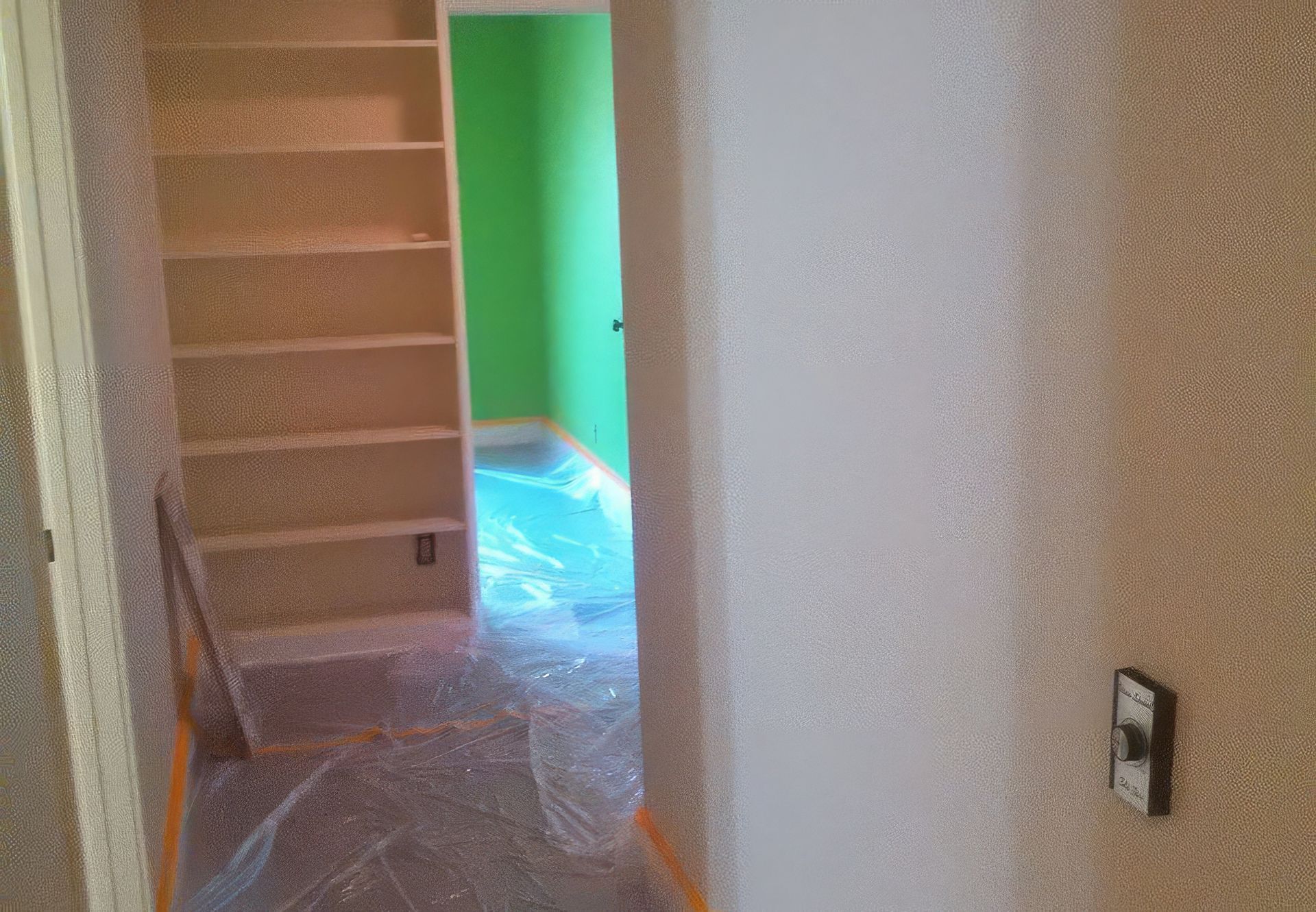 A hallway leading to a room with green walls and shelves.