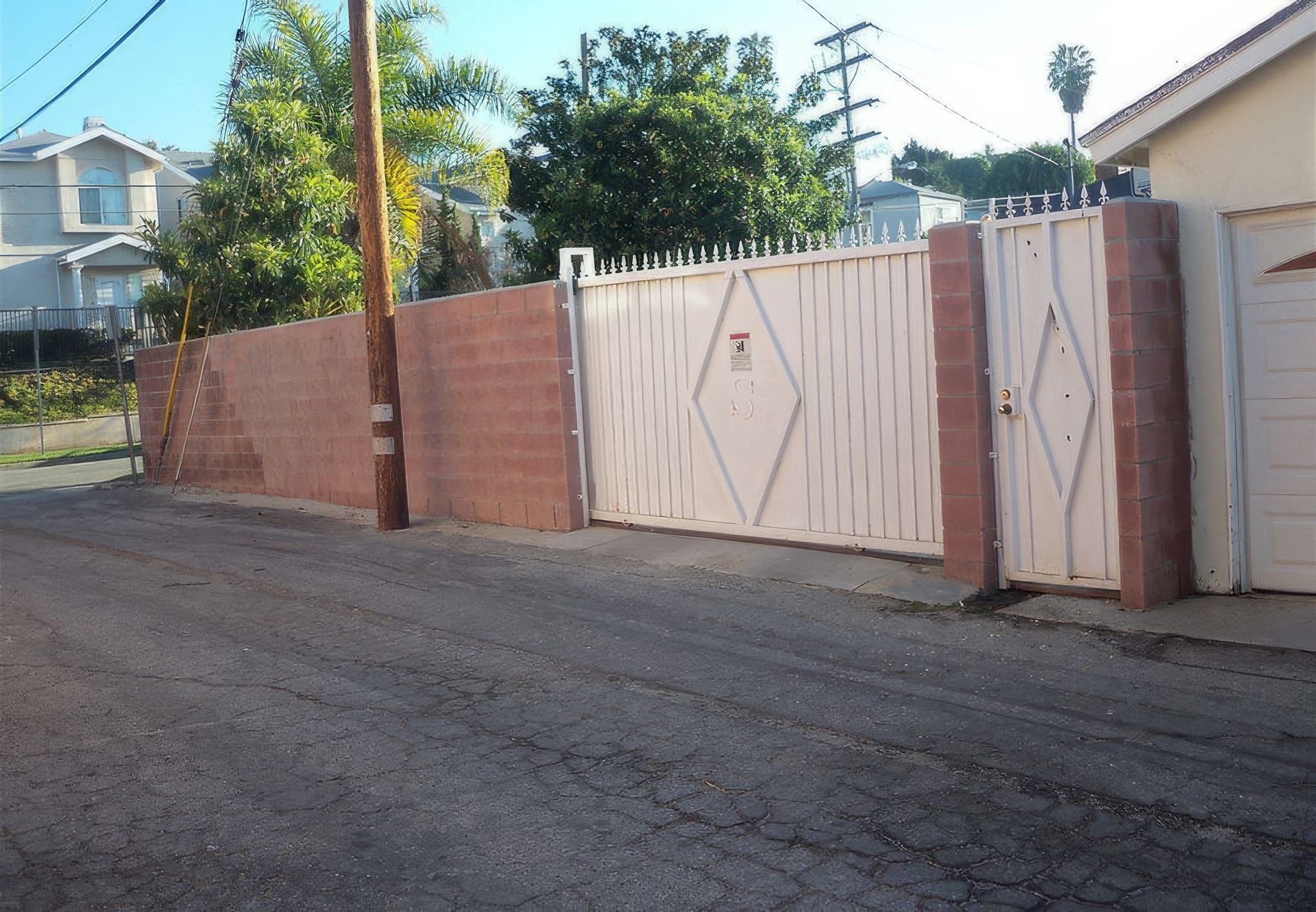 A white gate is surrounded by a brick wall