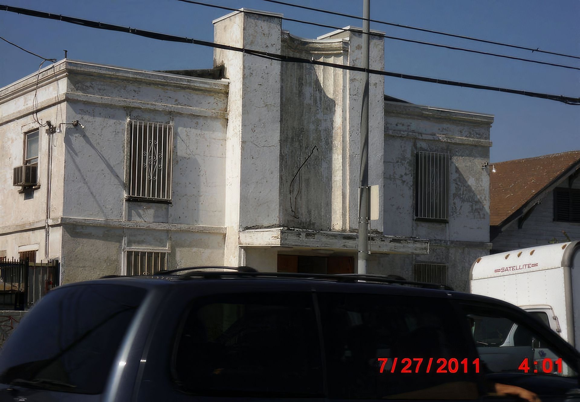 A black suv is parked in front of a white building on 7/27/2011
