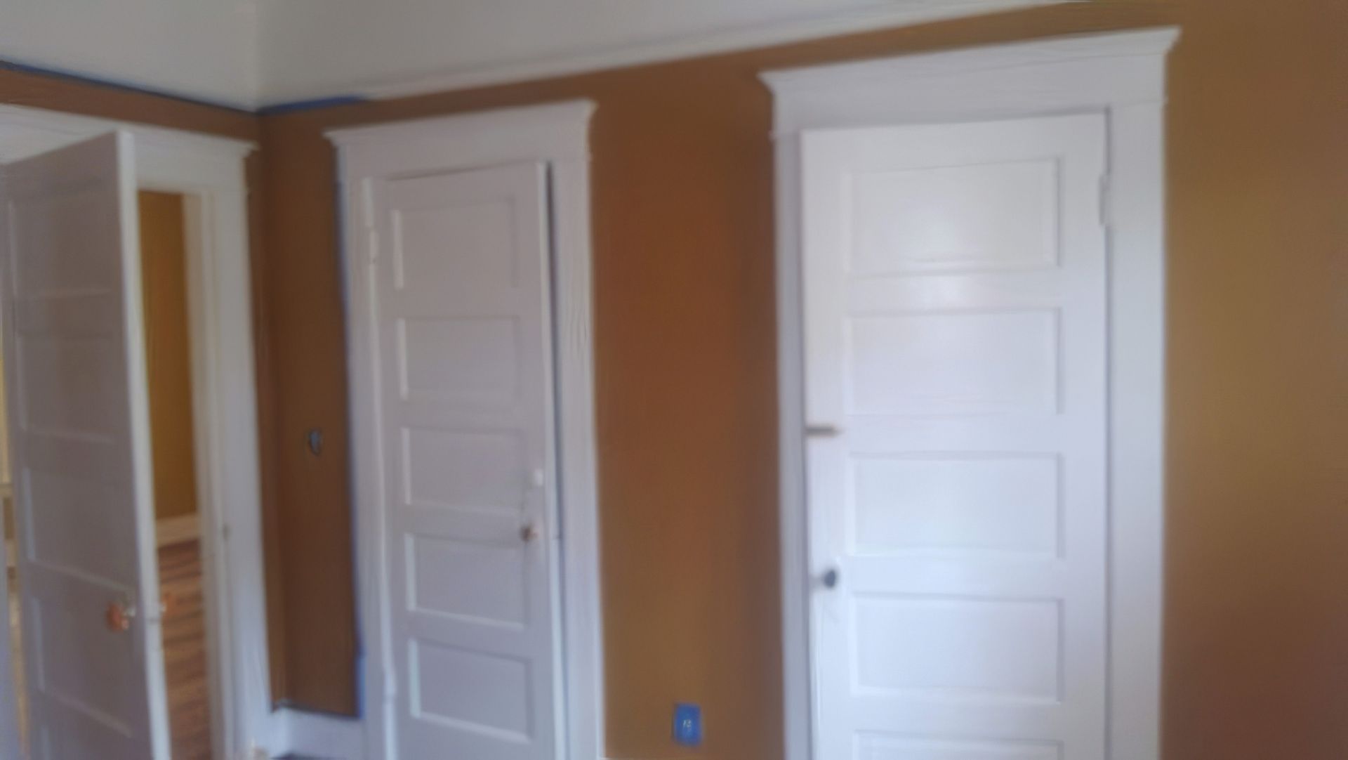 Two white doors in a room with brown walls