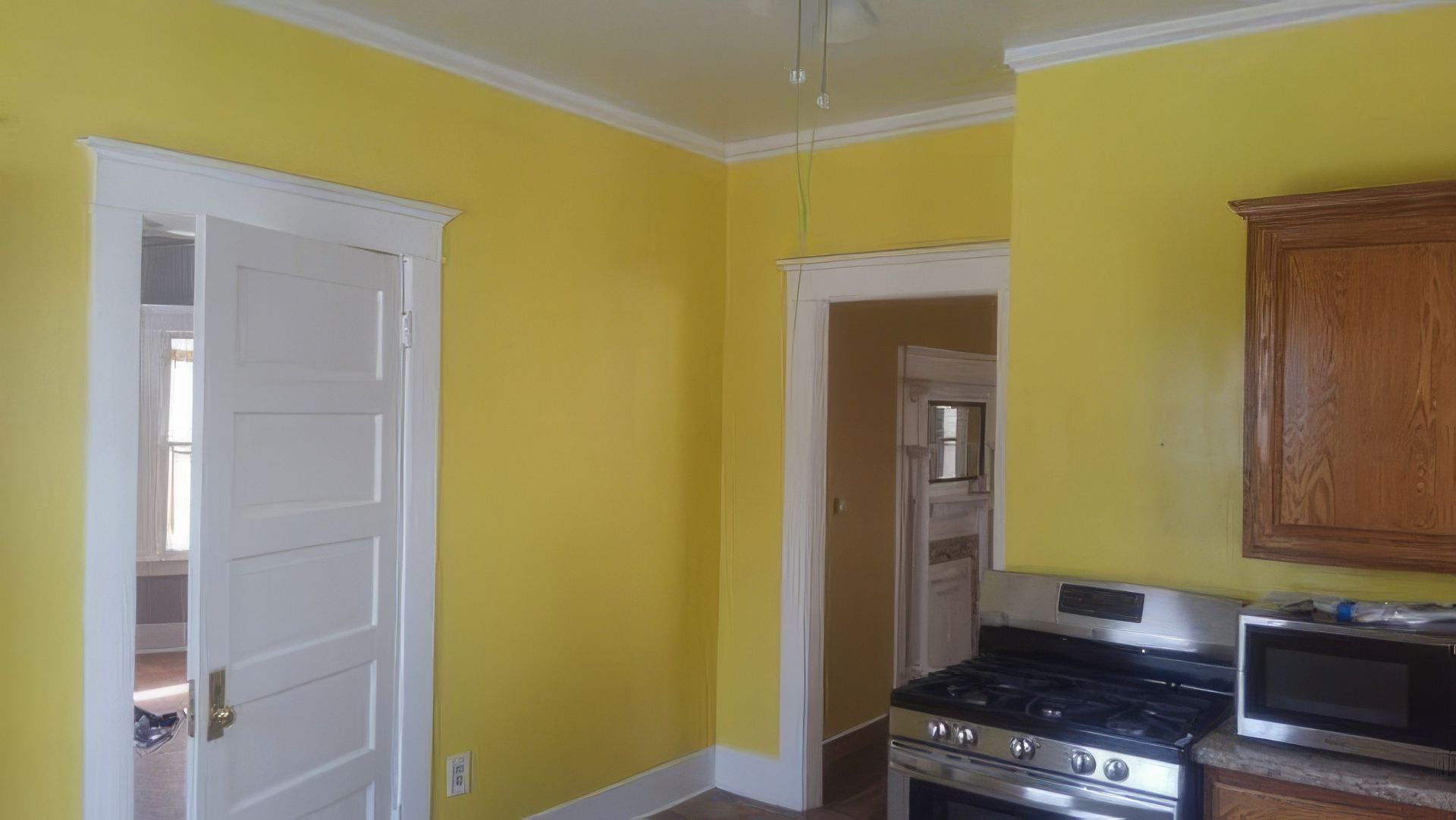 A kitchen with yellow walls and a stove and microwave.