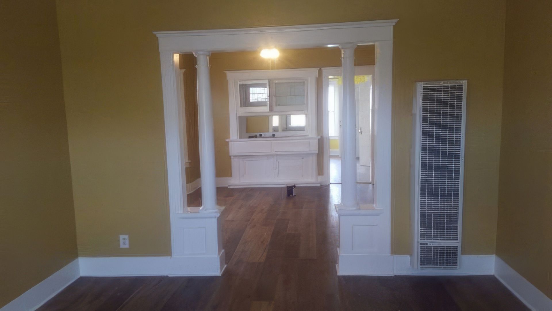 An empty living room with hardwood floors and yellow walls.