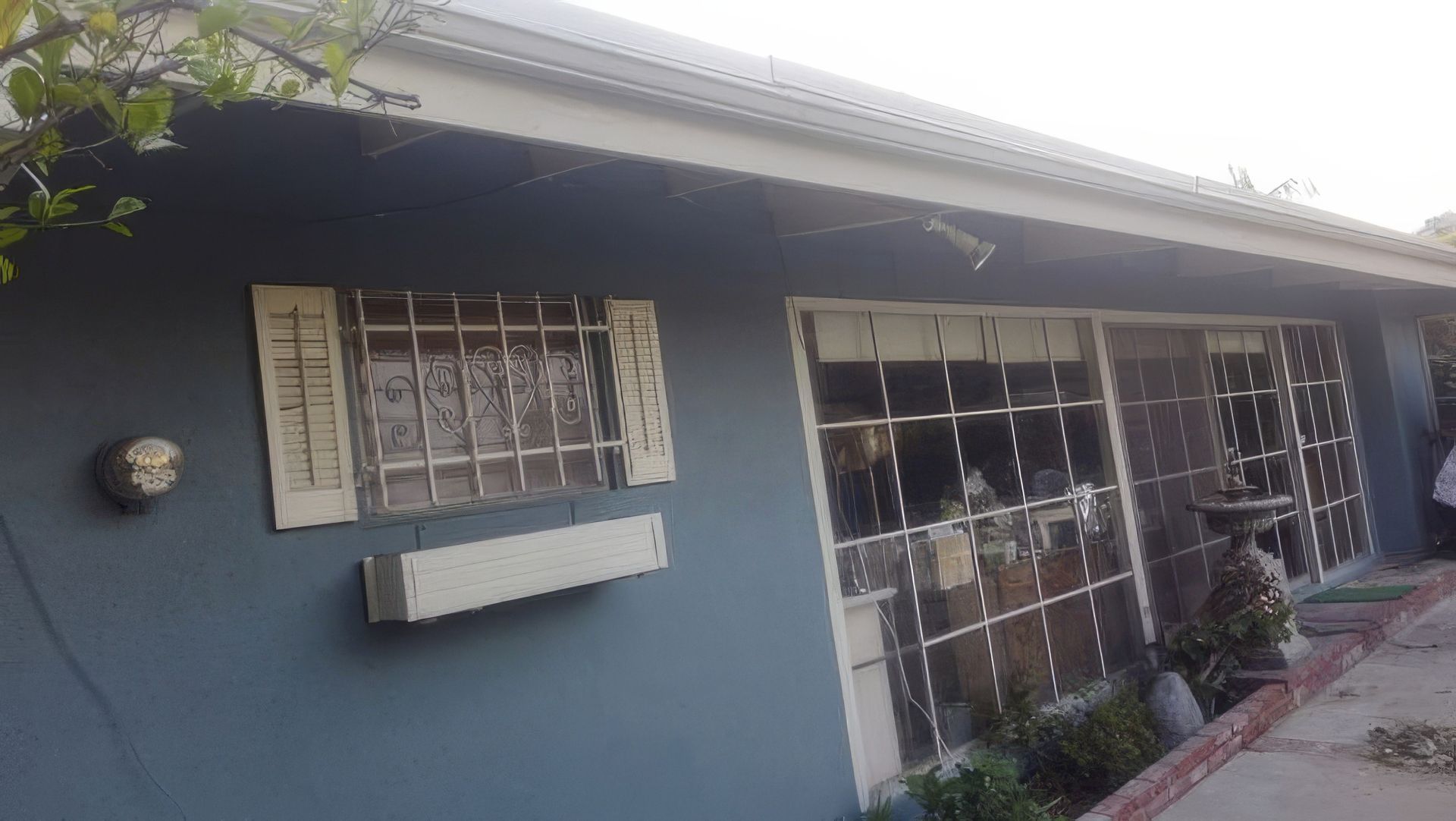 A blue house with a white roof and shutters on the windows.