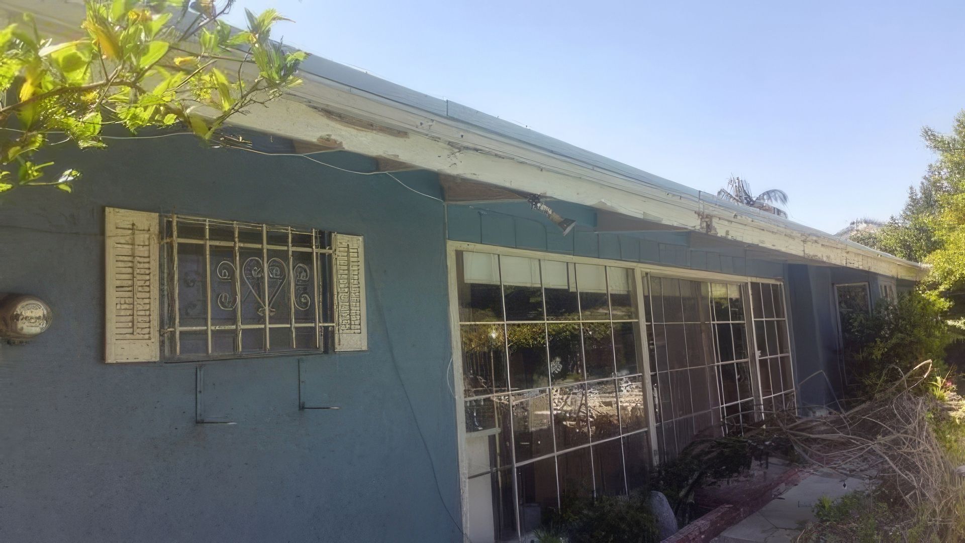 A blue house with a white roof and a lot of windows.