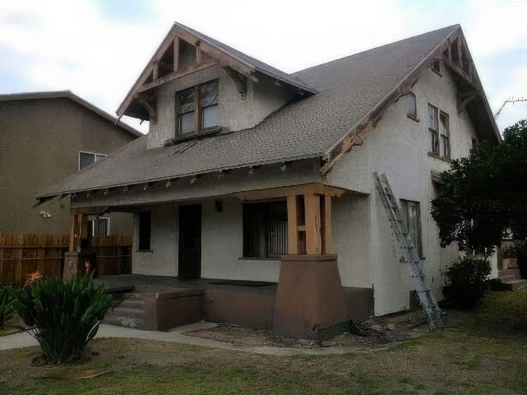 A white house with a brown roof and a ladder in front of it.