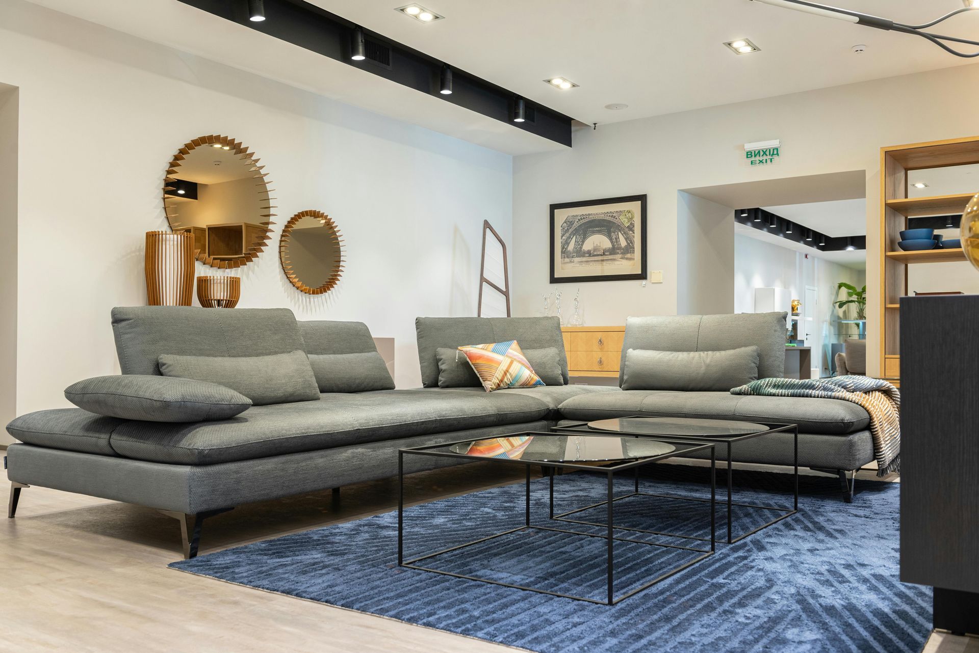 A living room with a gray sectional couch , two coffee tables , and a blue rug.