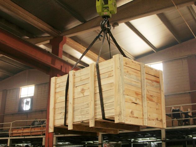 A large wooden box is being lifted by a crane.